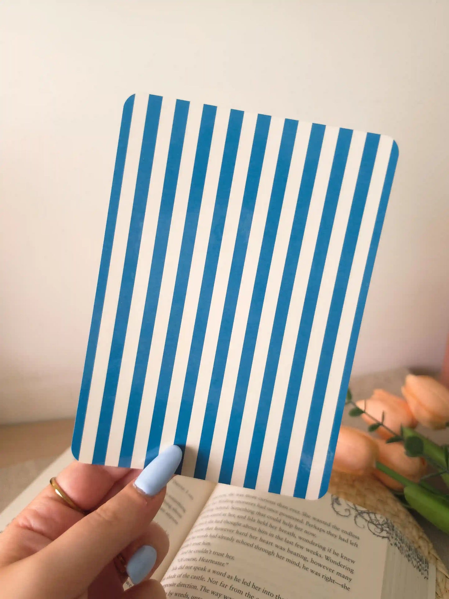 A hand holding an e-reader insert with bold blue and white vertical stripes.