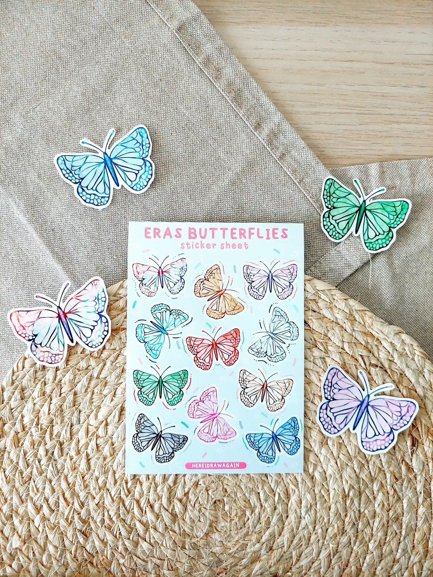 Butterfly sticker sheet featuring colorful butterflies inspired by Taylor Swift eras, photographed on a woven mat.