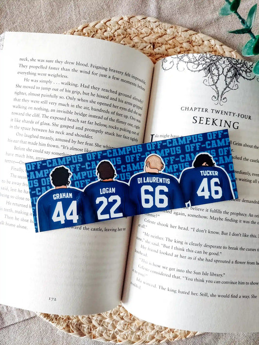 Off Campus inspired bookmark displayed on an open book, featuring illustrations of "Graham 44", "Logan 22", "Di Laurentis 66" and "Tucker 46" from behind in their jerseys on the front, and a blue Off Campus text pattern on the back.