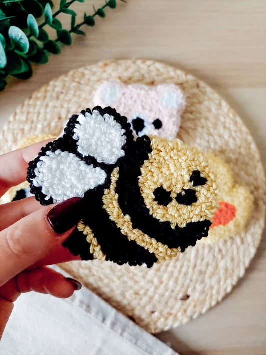 Handmade punch needle coaster, featuring a cute yellow and black bumblebee design with white wings.
