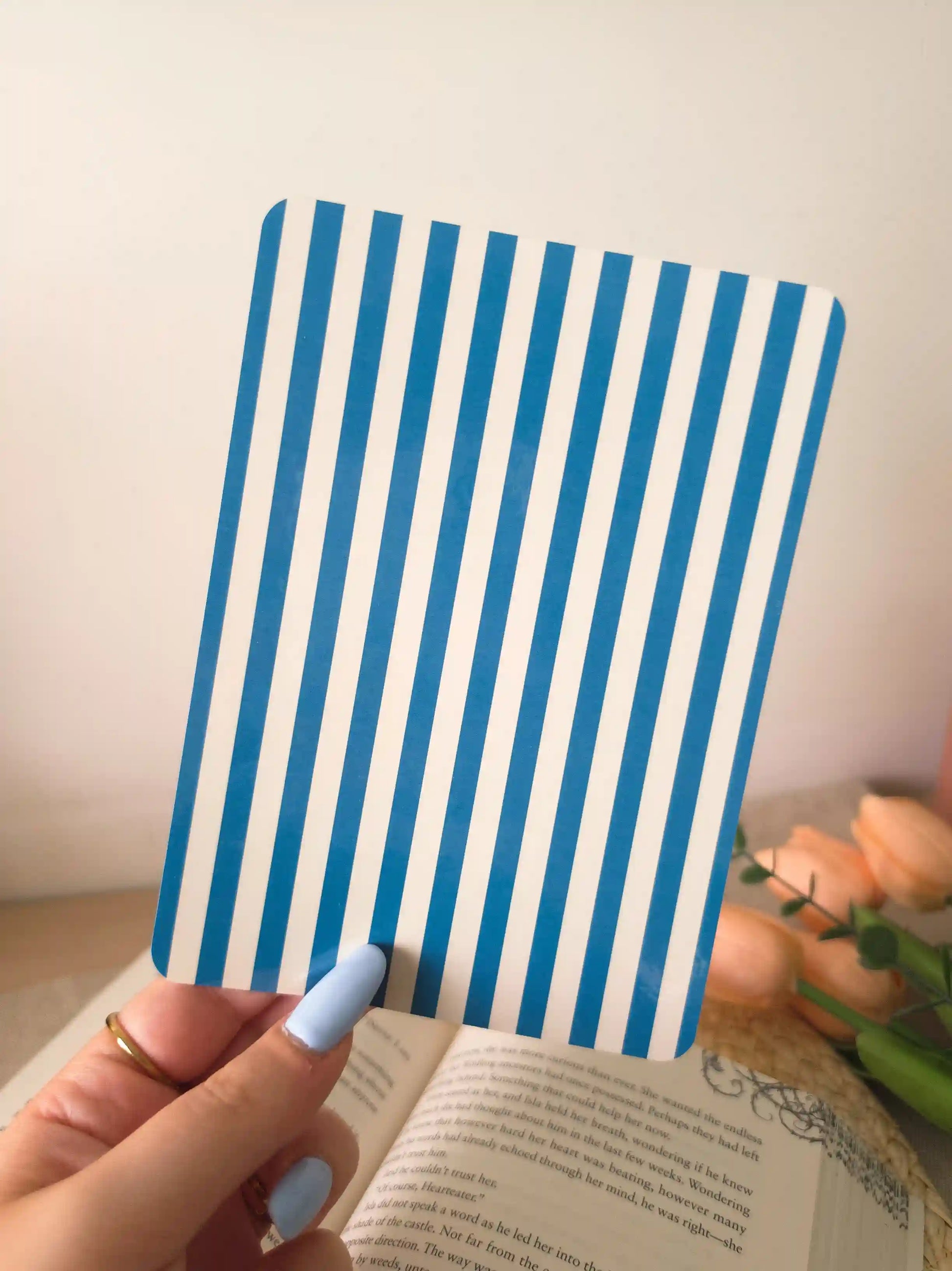 A hand holding an e-reader insert with bold blue and white vertical stripes.