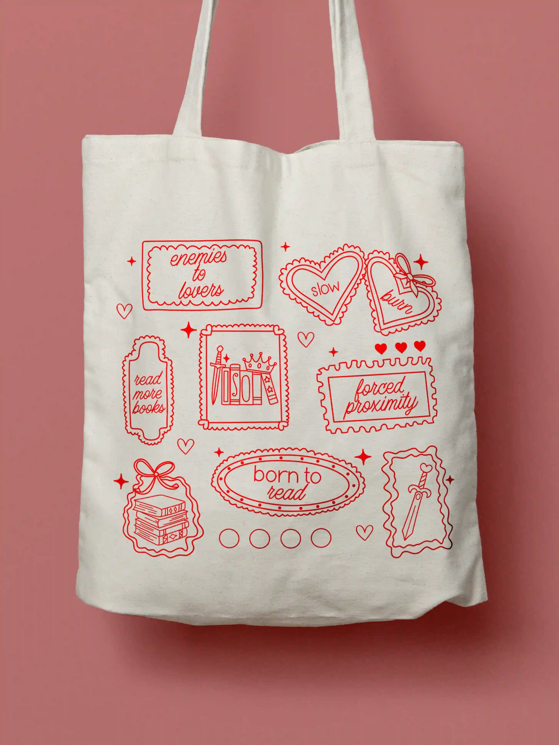 A canvas tote bag featuring red line-art illustrations styled as vintage stamps, with bookish phrases and tropes including "enemies to lovers," "slow burn," "read more books," "forced proximity," and "born to read," alongside drawings of books, a crown, a sword, and decorative hearts and sparkles. Photographed against a red background.