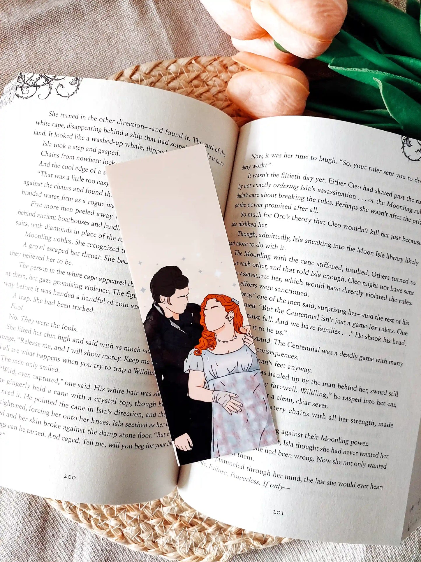Bookmark inspired by Bridgerton featuring an illustration of Penelope and Colin, displayed on an open book over a woven mat with decorative plants. 