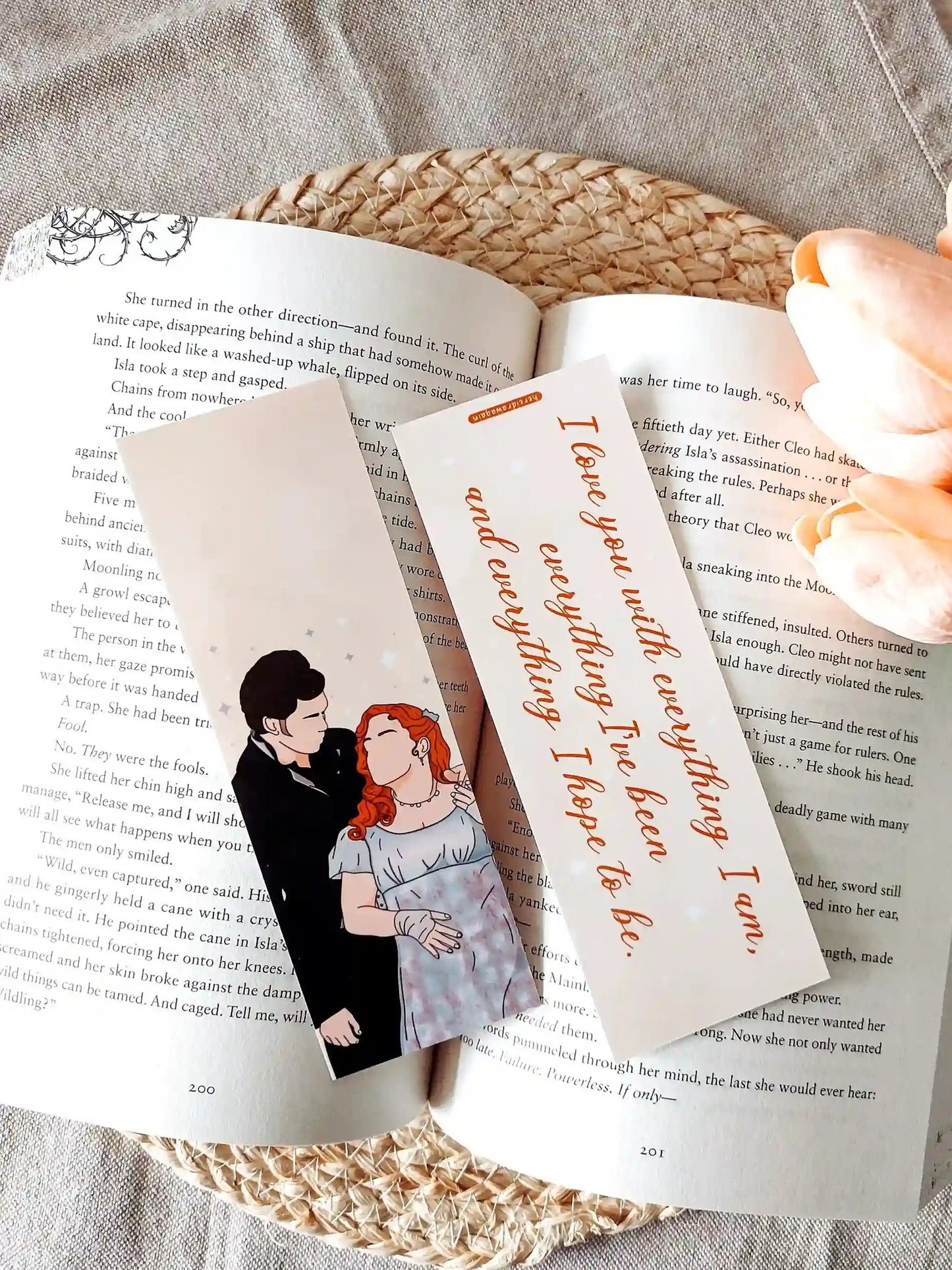 Bookmark inspired by Bridgerton featuring an illustration of Penelope and Colin on the front and the quote "I love you with everything I am, everything I've been and everything I hope to be" on the back, displayed on an open book over a woven mat with decorative plants. 