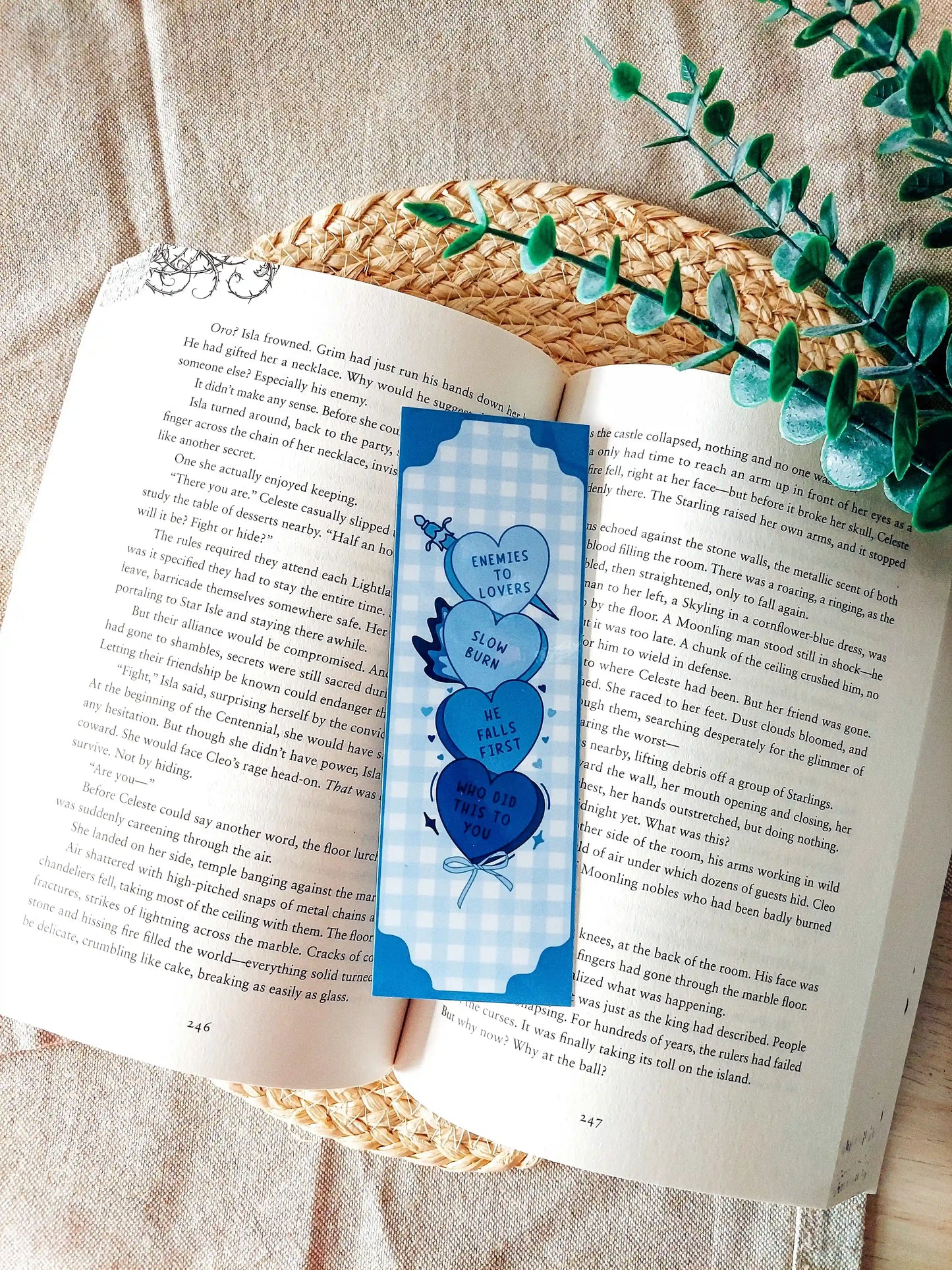 Candy hearts tropes bookmark placed on an open book, featuring Enemies to Lovers, Slow Burn, He Falls First and Who Did This To You in shades of blue.