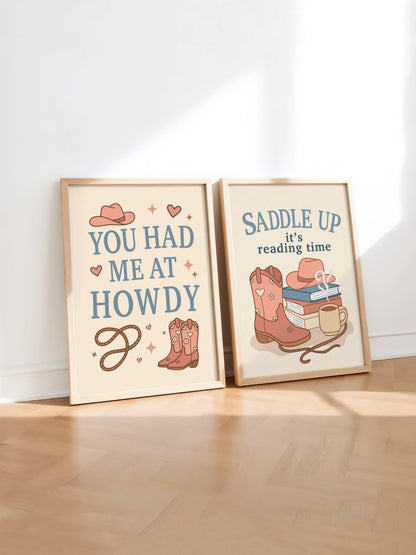 Set of two art prints inspired by cowboy romance books, featuring western-themed illustrations and the text "You Had Me at Howdy" on one and "Saddle Up, it’s reading time" on the other, displayed side by side in frames.
