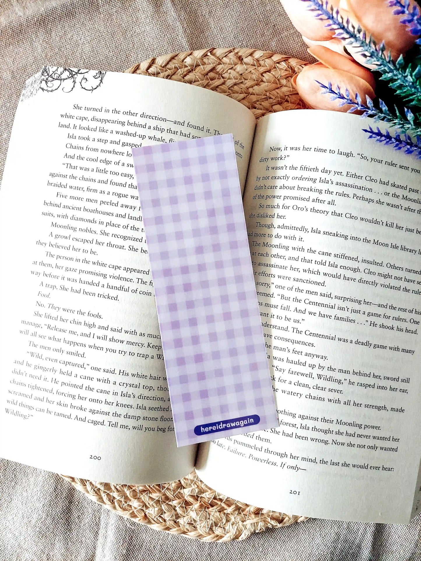 Bookmark featuring a purple gingham pattern, displayed on an open book over a woven mat. 