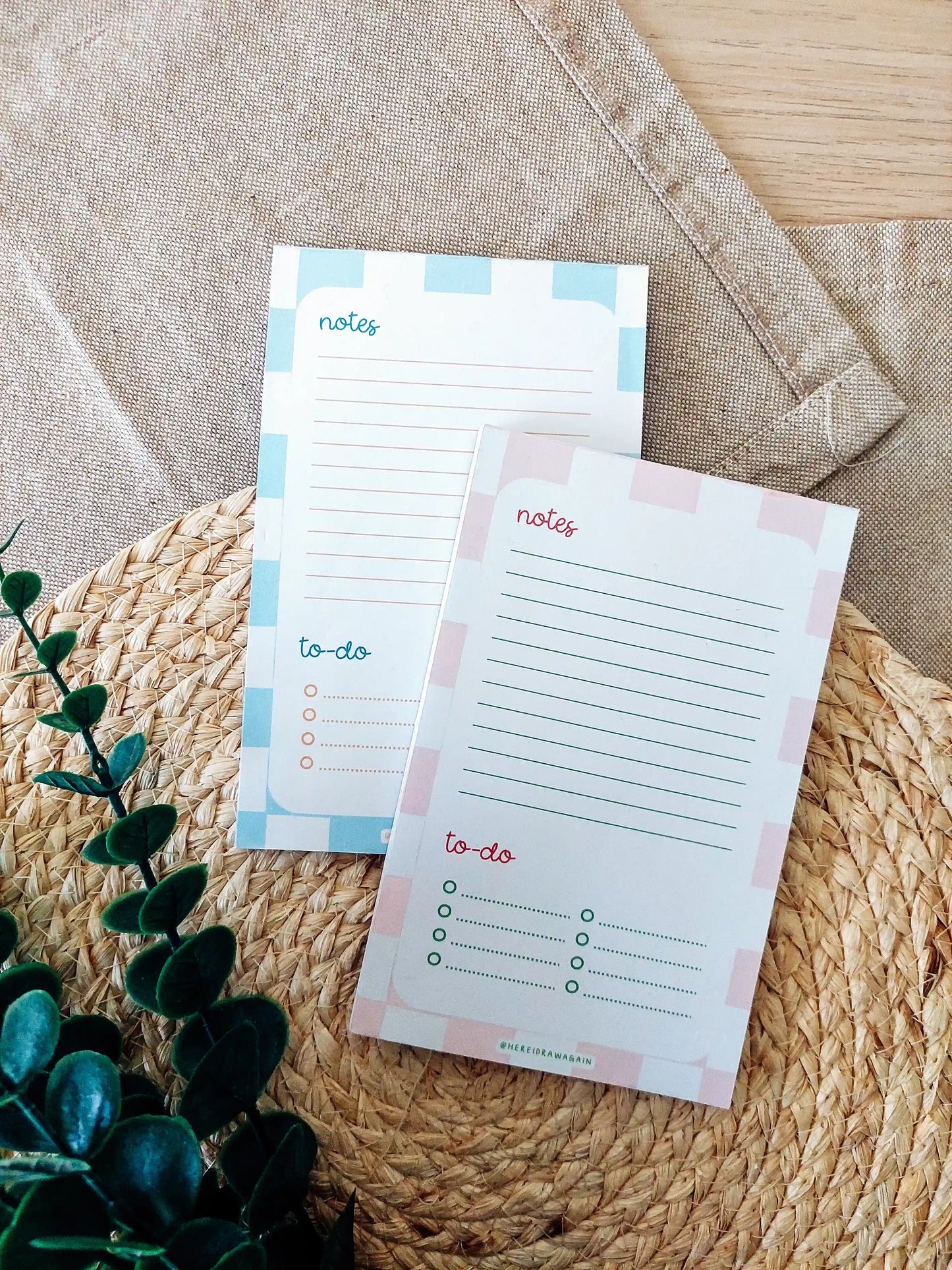 Two notes and to-do notepads, each featuring a lined notes section at the top and a checklist-style to-do section at the bottom, photographed on a woven surface with decorative flowers.