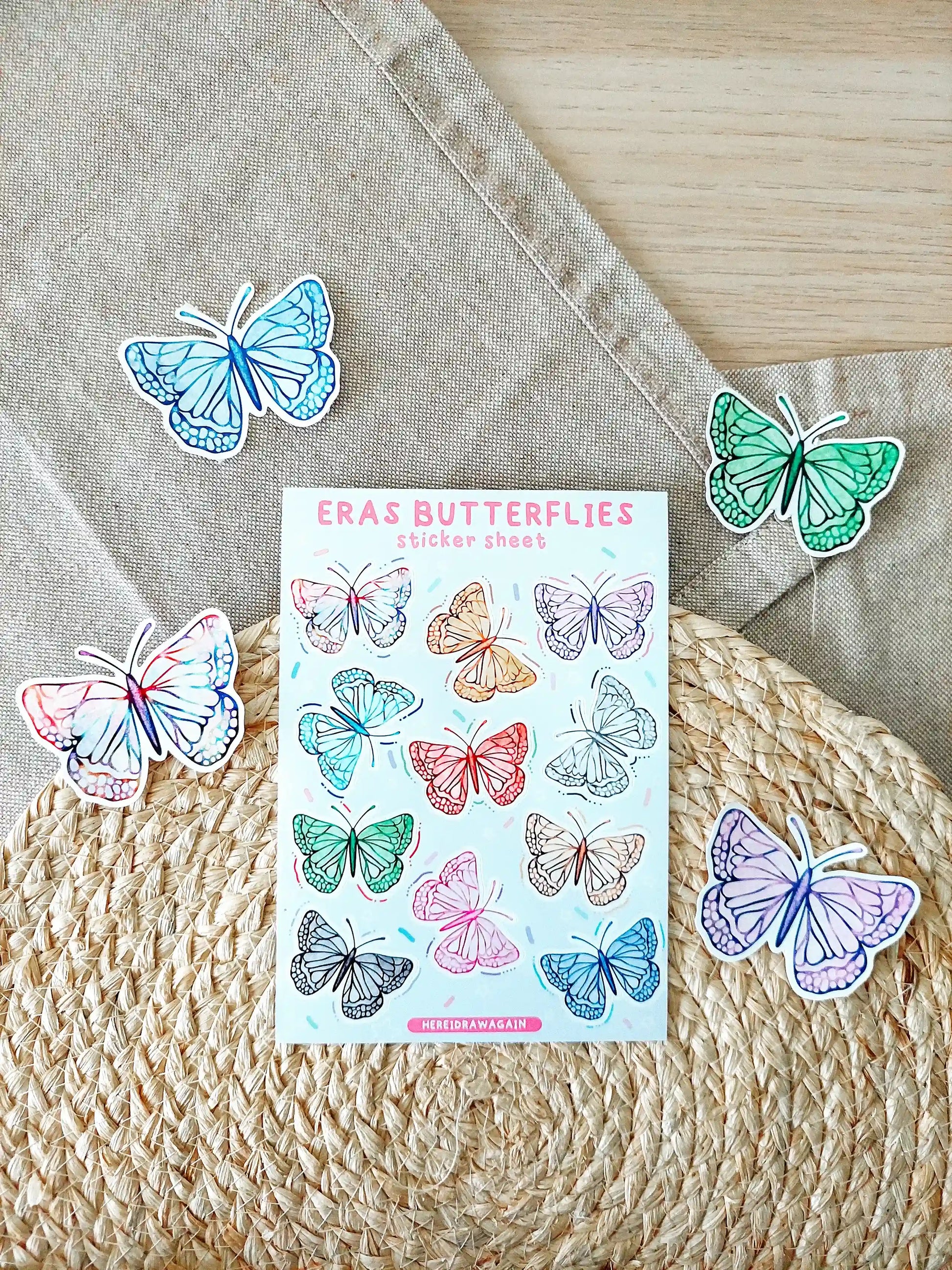 Butterfly sticker sheet featuring colorful butterflies inspired by Taylor Swift eras, photographed on a woven mat.