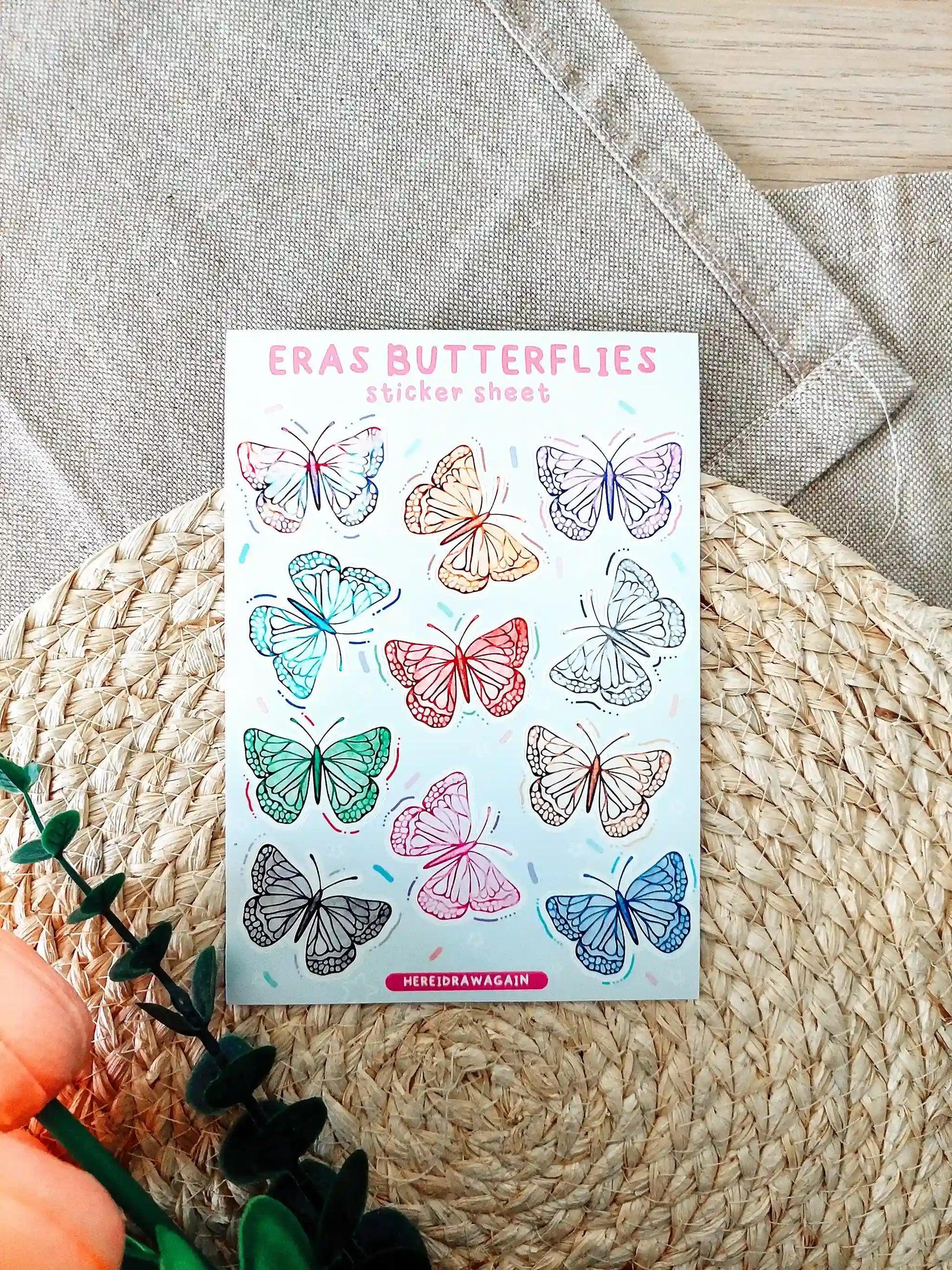 Butterfly sticker sheet featuring colorful butterflies inspired by Taylor Swift eras, photographed on a woven mat.
