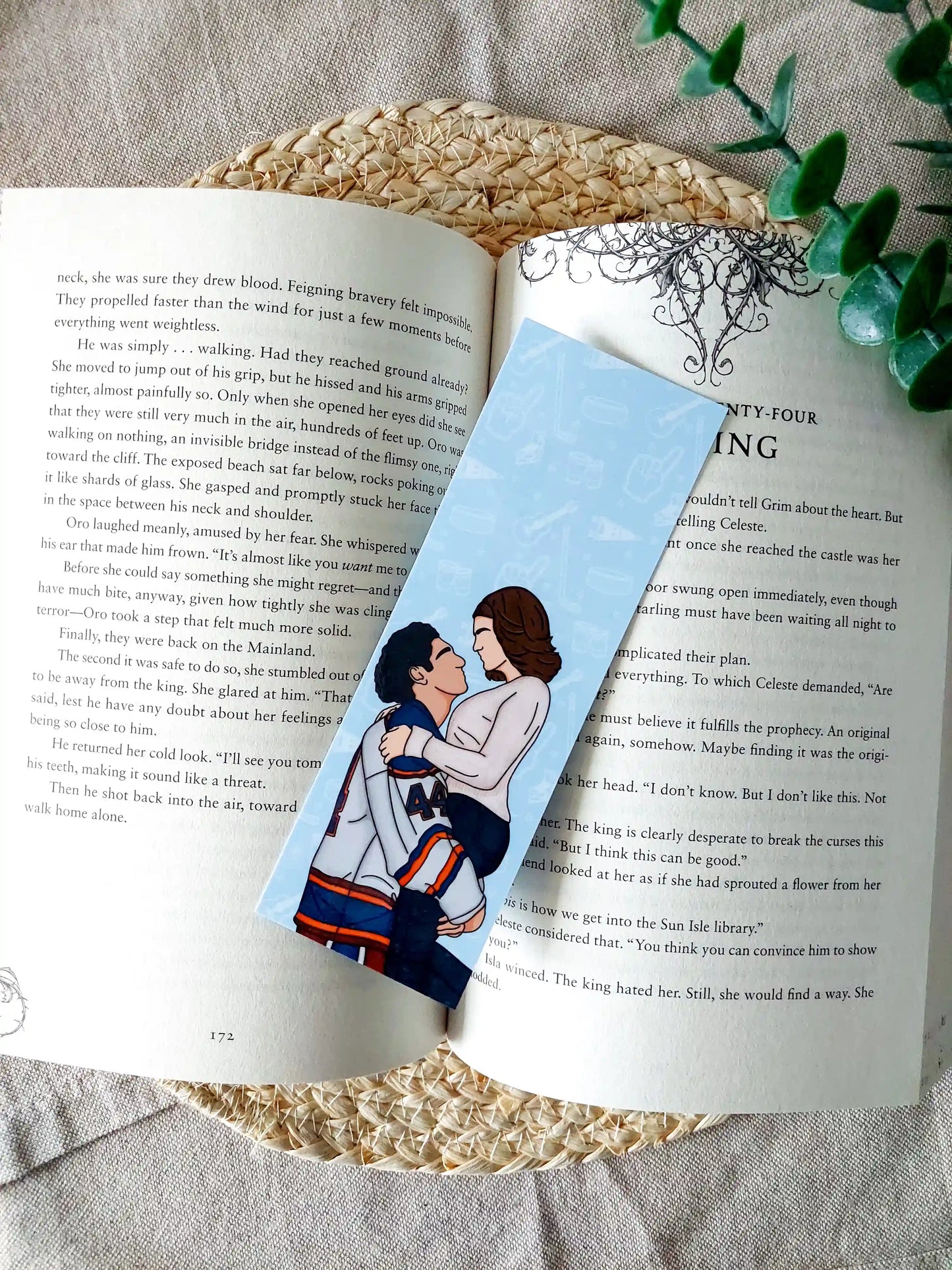 Off Campus inspired bookmark displayed on an open book, featuring an illustration of Graham and Hannah.
