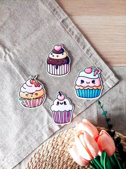 Set of four holographic cupcake vinyl stickers with pastel colors and kawaii faces, photographed on a woven mat.
