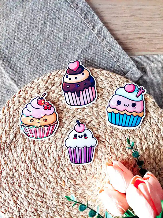Set of four holographic cupcake vinyl stickers with pastel colors and kawaii faces, photographed on a woven mat.