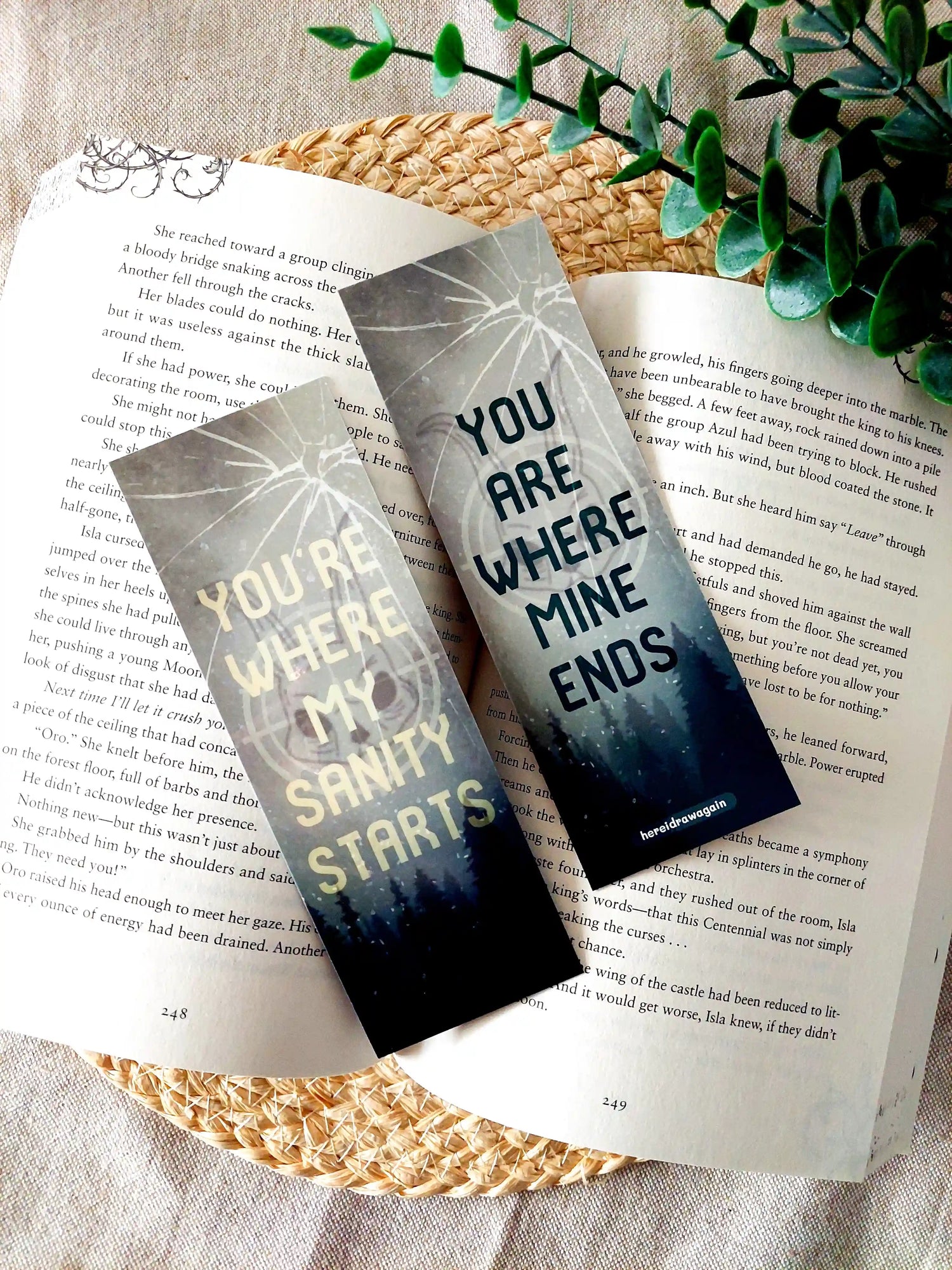 Leave Me Behind inspired bookmark displayed on an open book, featuring a forest and cracked glass design with the quote "You're where my sanity starts" and "You are where mine ends" split across front and back.