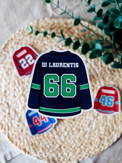 Off Campus inspired navy hockey jersey with "Di Laurentis 66" on it, placed on a textured surface with greenery.