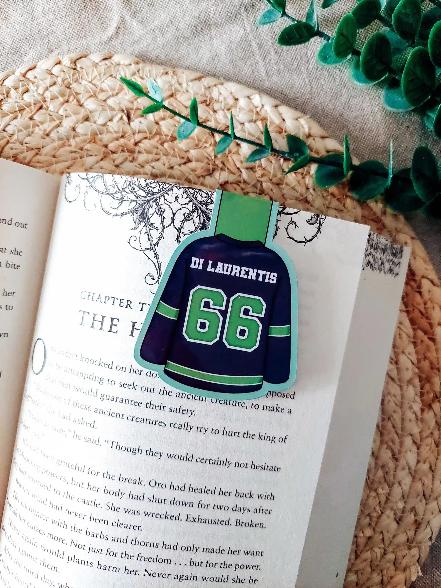 Off Campus inspired hockey jersey magnetic bookmark clipped onto an open book, showing the green and navy jersey design with "Di Laurentis 66" on the back.