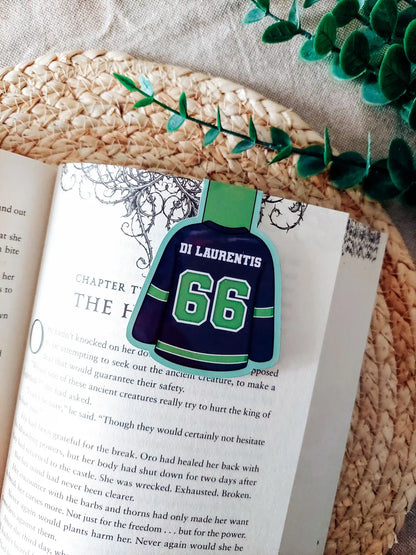 Off Campus inspired hockey jersey magnetic bookmark clipped onto an open book, showing the green and navy jersey design with "Di Laurentis 66" on the back.