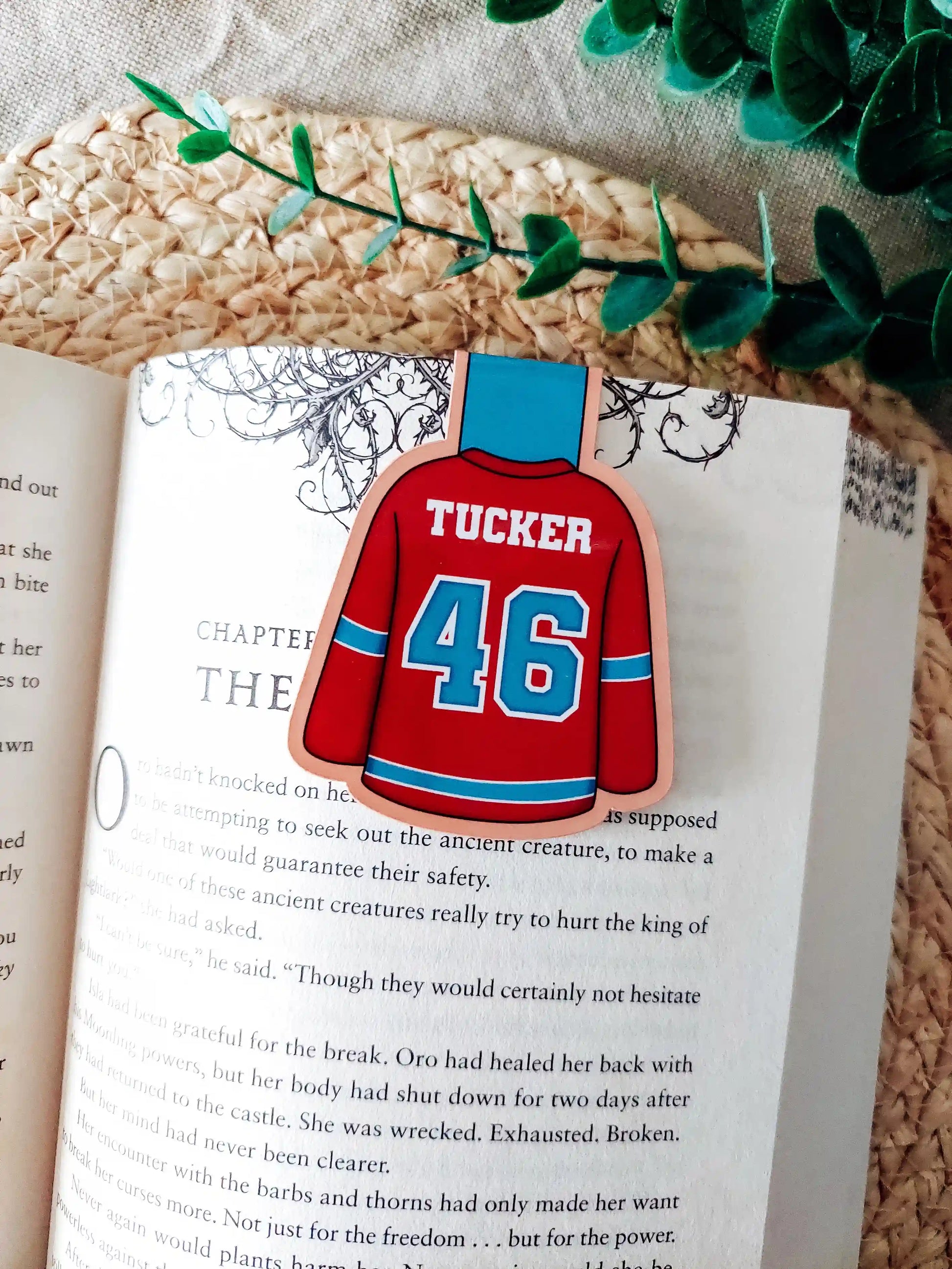 Off Campus inspired hockey jersey magnetic bookmark clipped onto an open book, showing the blue and red jersey design with "Tucker 46" on the back.