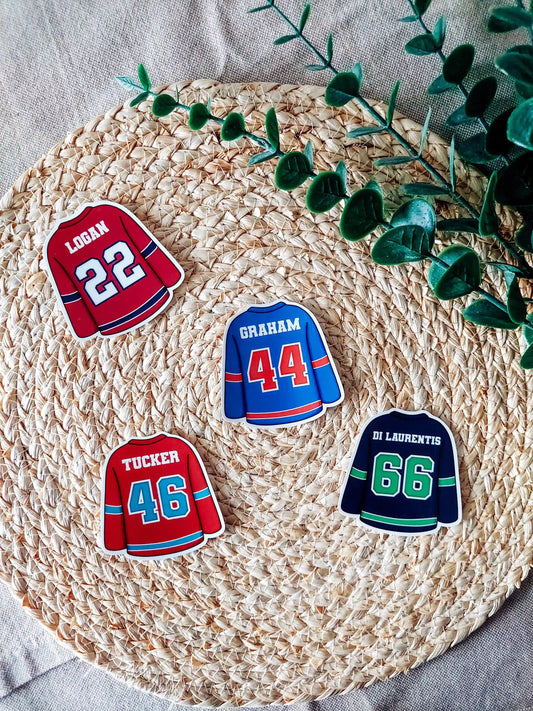 Four hockey jersey stickers on a rattan placemat, featuring Off Campus players: Logan 22, Tucker 46, Graham 44 and Di Laurentis 66.