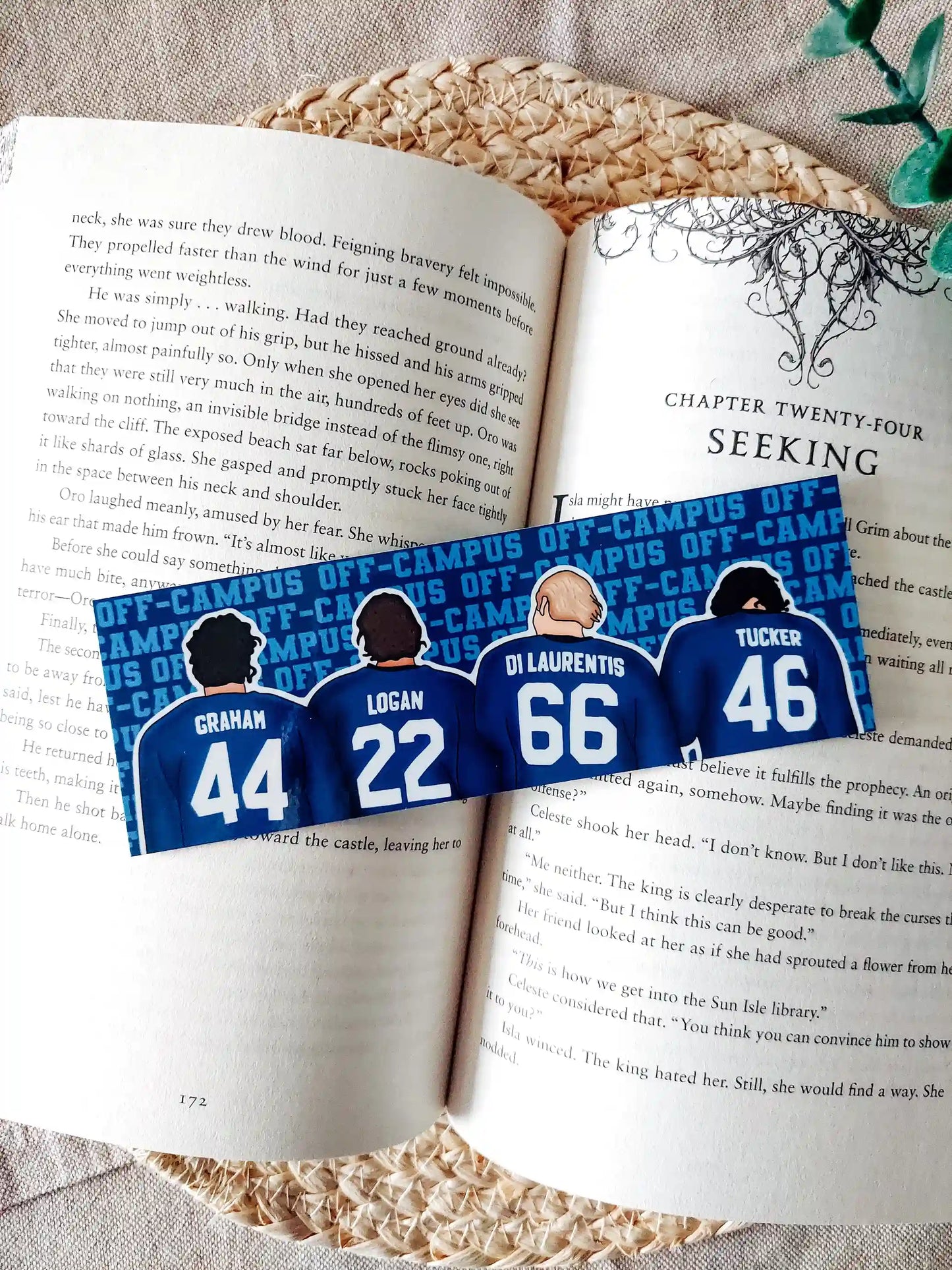 Off Campus inspired bookmark displayed on an open book, featuring illustrations of "Graham 44", "Logan 22", "Di Laurentis 66" and "Tucker 46" from behind in their jerseys on the front, and a blue Off Campus text pattern on the back.