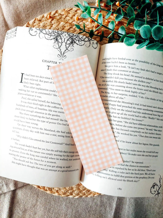 Bookmark with an orange gingham pattern, resting on an open book.