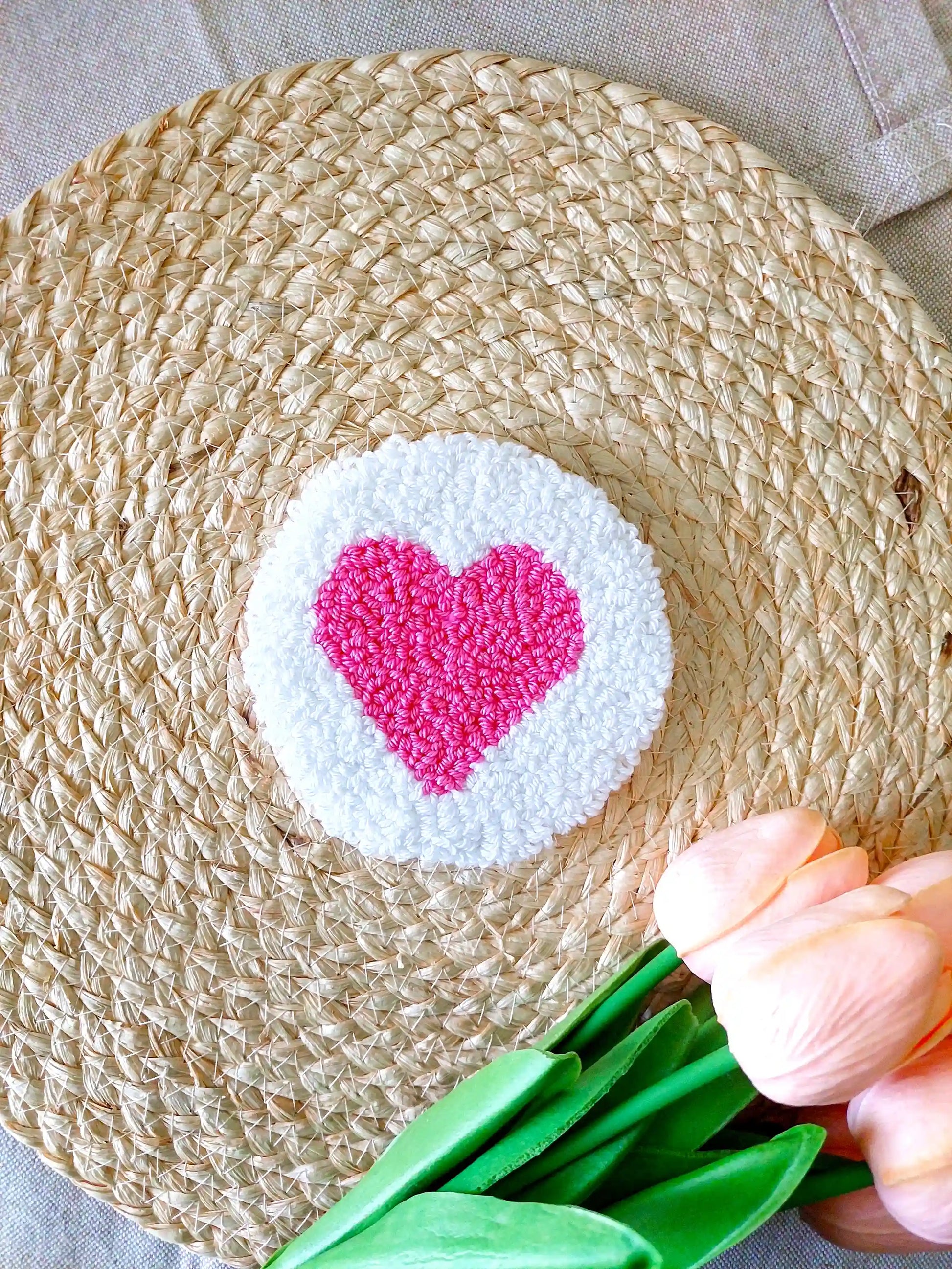Handmade punch needle coaster with a white background and a bright pink heart in the middle.