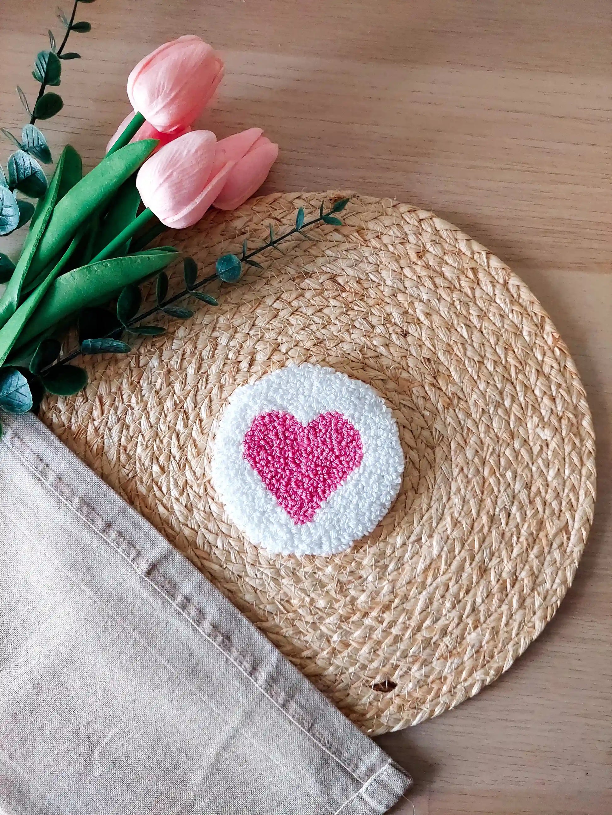 Handmade punch needle coaster with a white background and a bright pink heart in the middle.