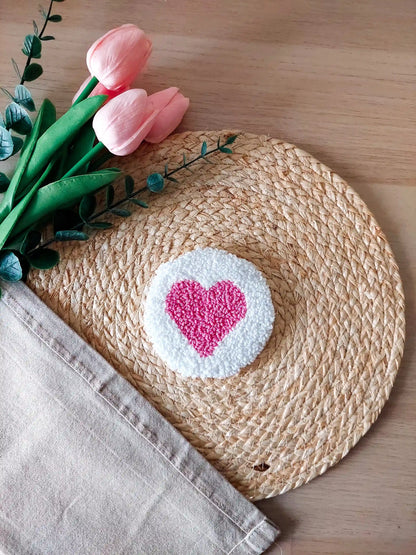 Handmade punch needle coaster with a white background and a bright pink heart in the middle.