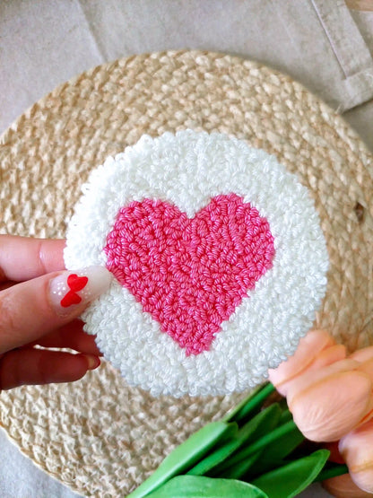 Handmade punch needle coaster with a white background and a bright pink heart in the middle.

