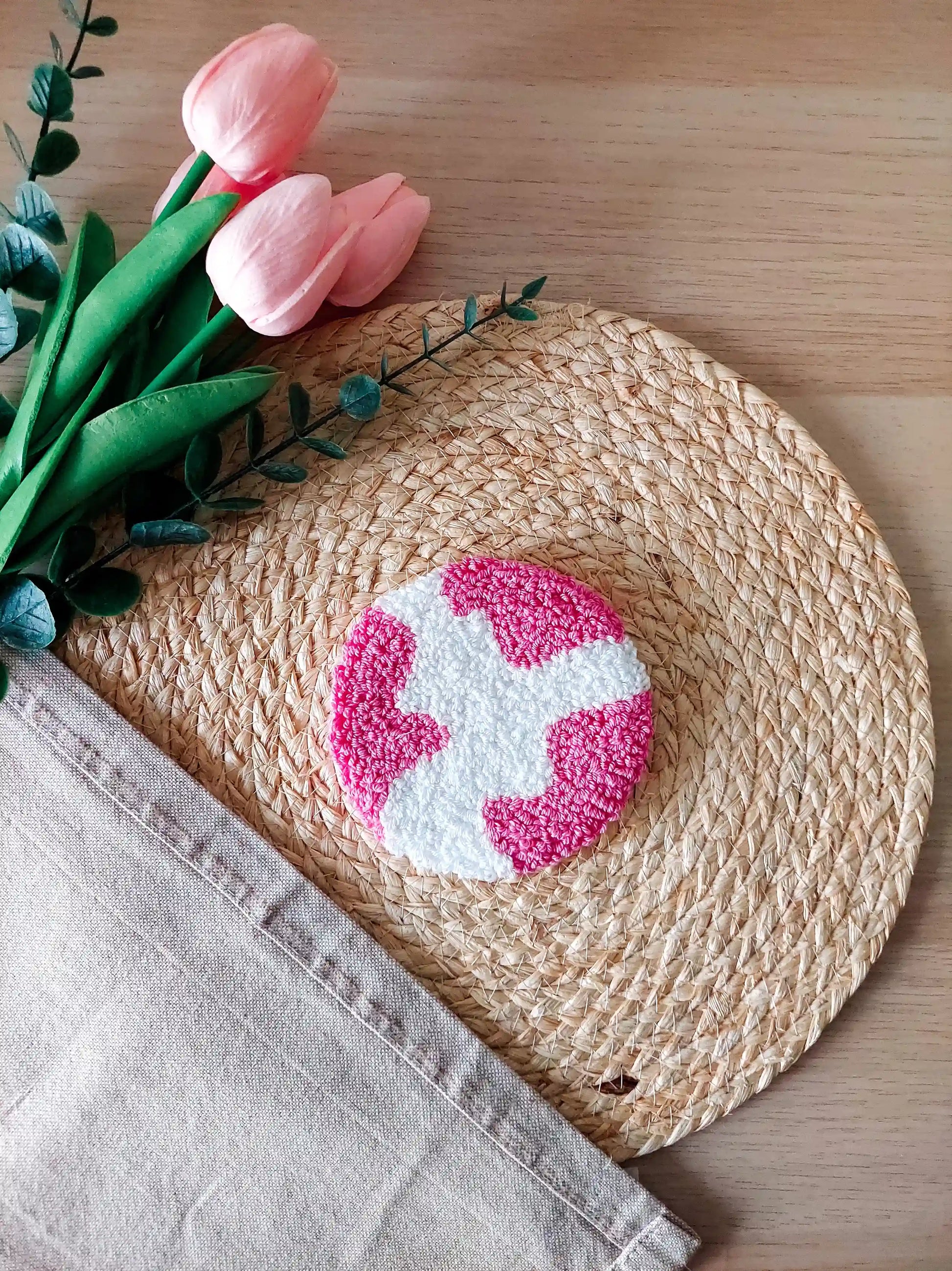 Handmade punch needle round coaster featuring an abstract white and hot pink shape. 