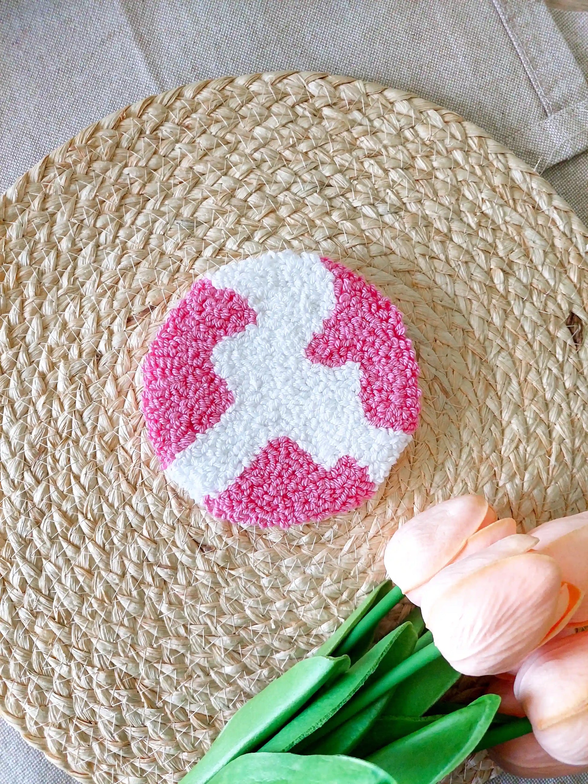 Handmade punch needle round coaster featuring an abstract white and hot pink shape. 