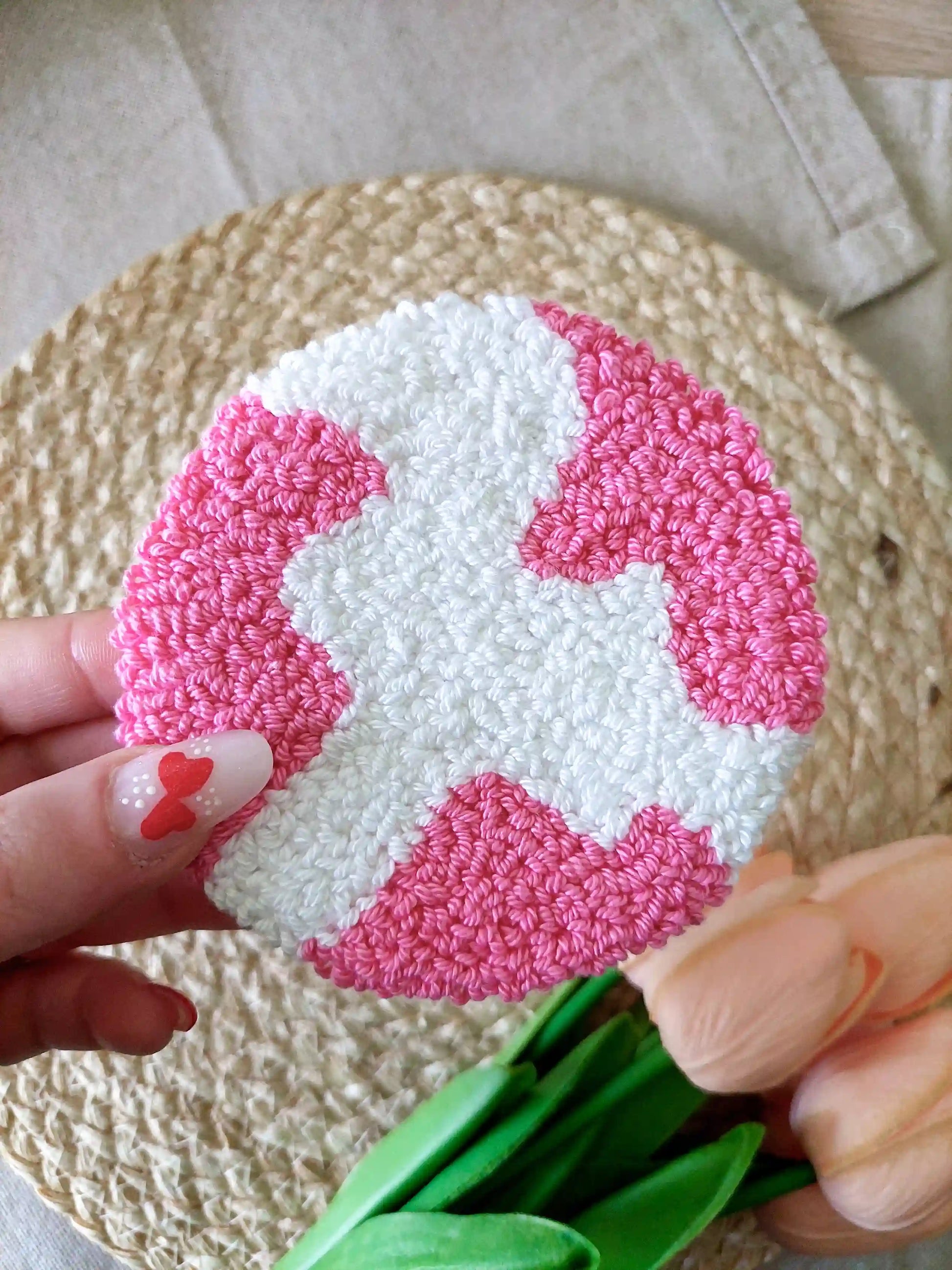 Handmade punch needle round coaster featuring an abstract white and hot pink shape. 