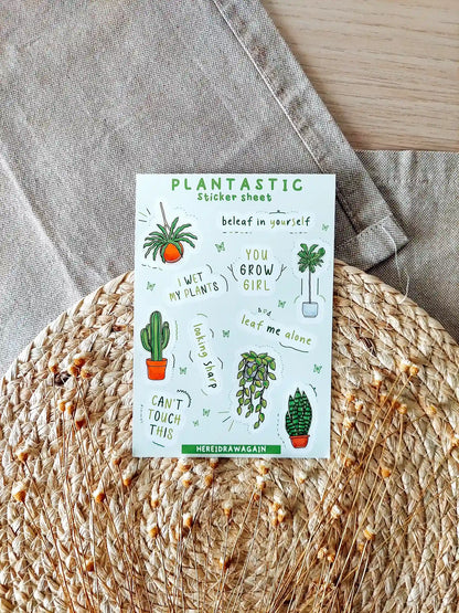 Plants themed sticker sheet featuring illustrated houseplants and plant related puns, photographed on a woven mat with decorative flowers.