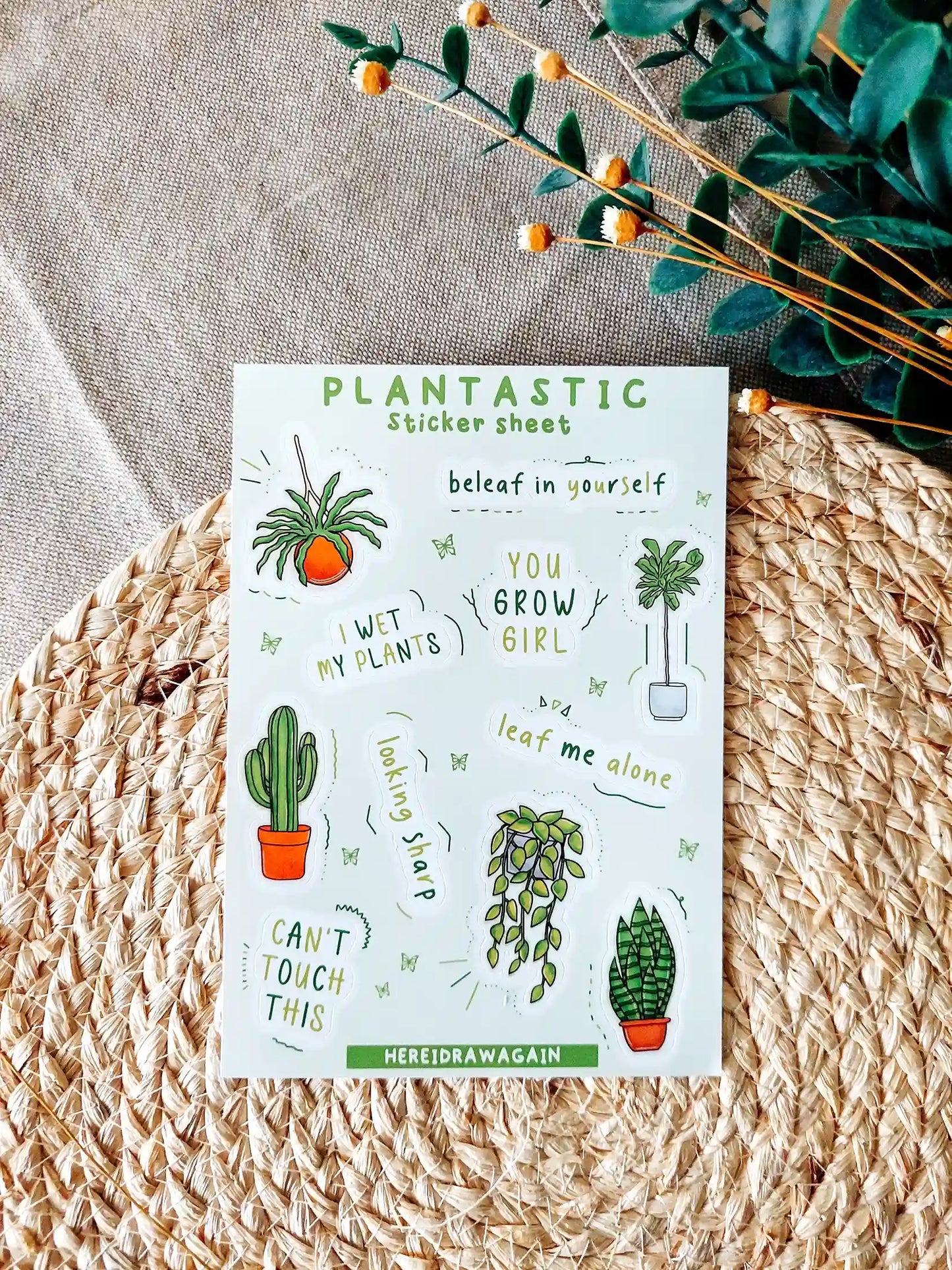 Plants themed sticker sheet featuring illustrated houseplants and plant related puns, photographed on a woven mat with decorative flowers.