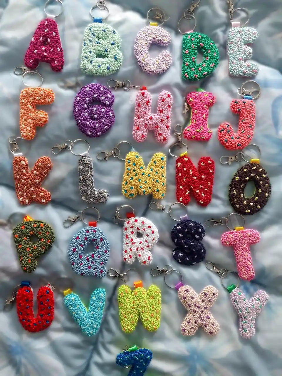 Colorful alphabet keychains on a textured surface.