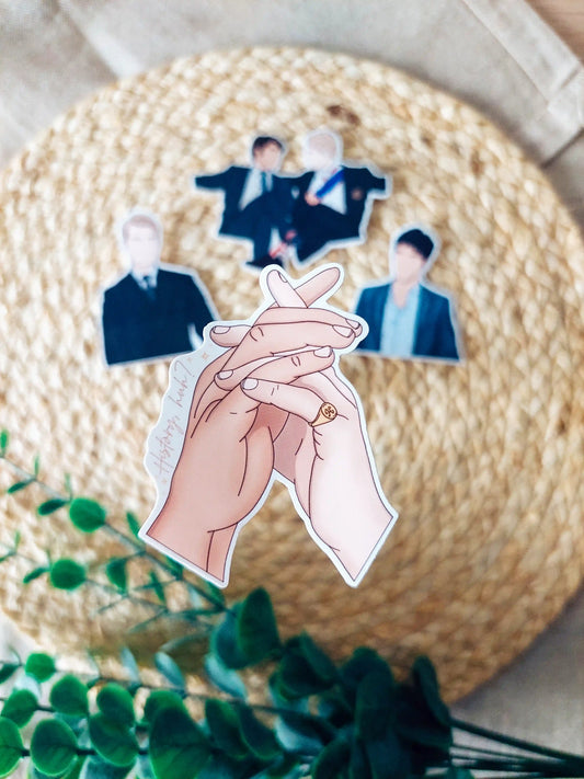 Close up photo of a vinyl sticker featuring intertwined hands inspired by Alex Claremont-Diaz and Prince Henry from Red, White & Royal Blue.