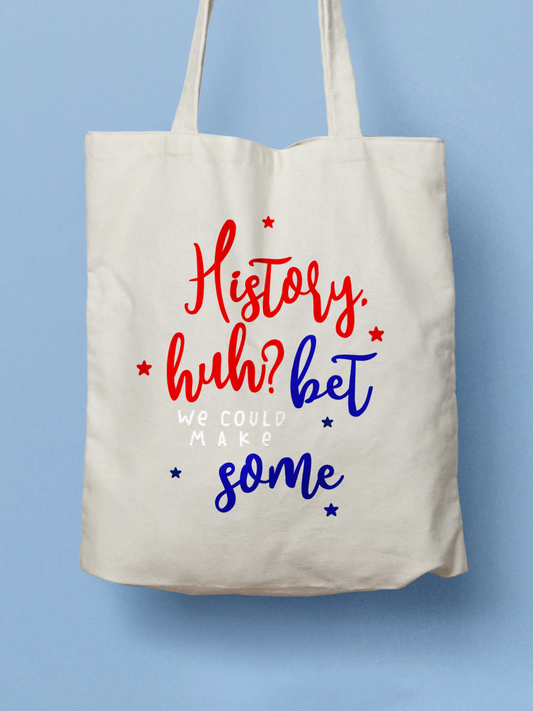 Cotton canvas tote bag inspired by Red, White and Royal Blue text reading "History, huh? Bet we could make some" in red, white and blue, photographed on a blue background.