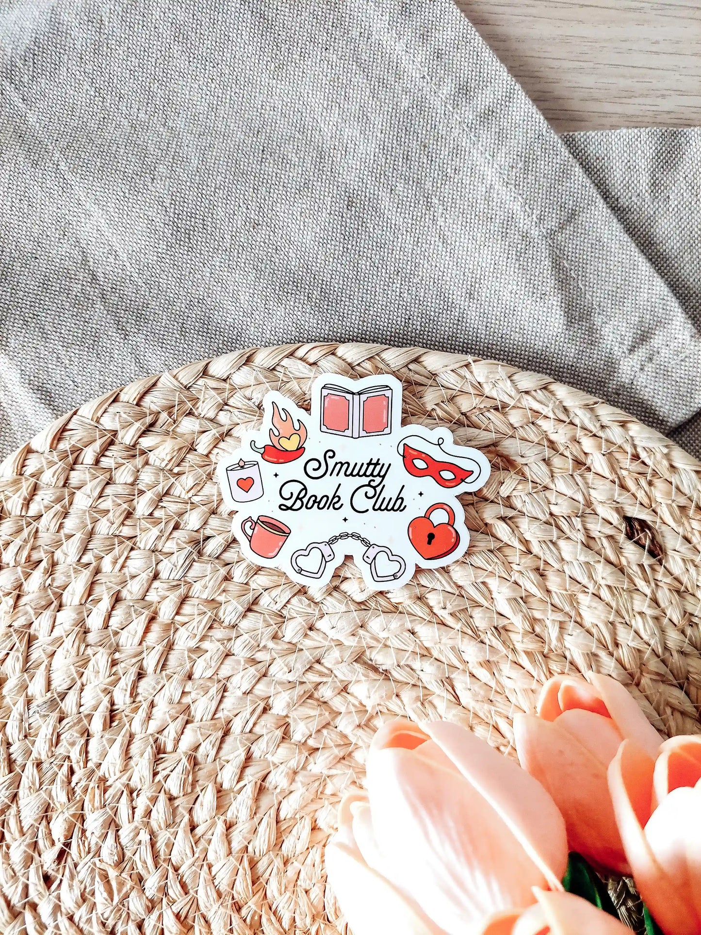 Vinyl sticker with the text "Smutty Book Club" surrounded by romance-themed illustrations including handcuffs, mask, heart lock.