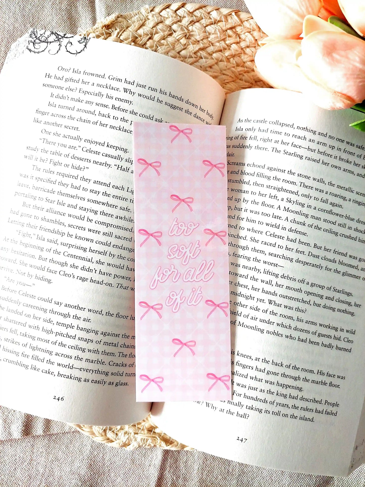 "Too Soft For All Of It" bookmark placed on an open book, featuring a pink floral pattern with bows and pink script text.