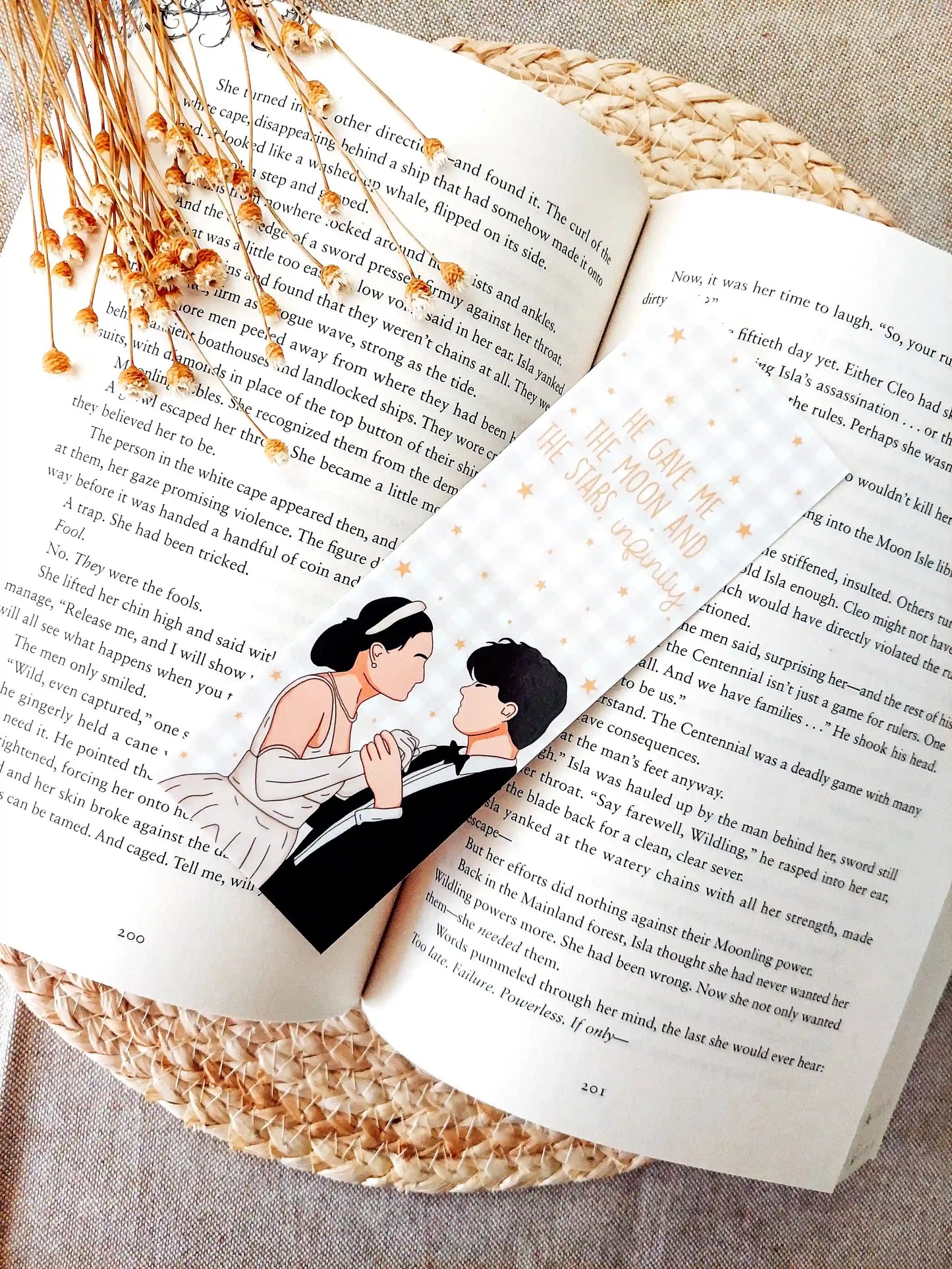 Bookmark inspired by The Summer I Turned Pretty, featuring Belly and Conrad with the quote "He gave me the moon and the stars, infinity." on a gold gingham background with little gold stars, resting on an open book.