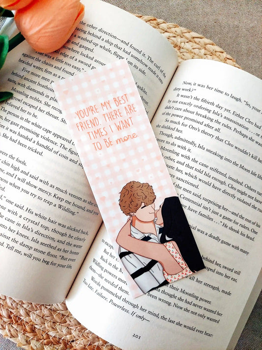 Bookmark inspired by The Summer I Turned Pretty, featuring Belly and Jeremiah with the quote "You’re my best friend. There are times I want to be more." on a pink gingham background, resting on an open book.