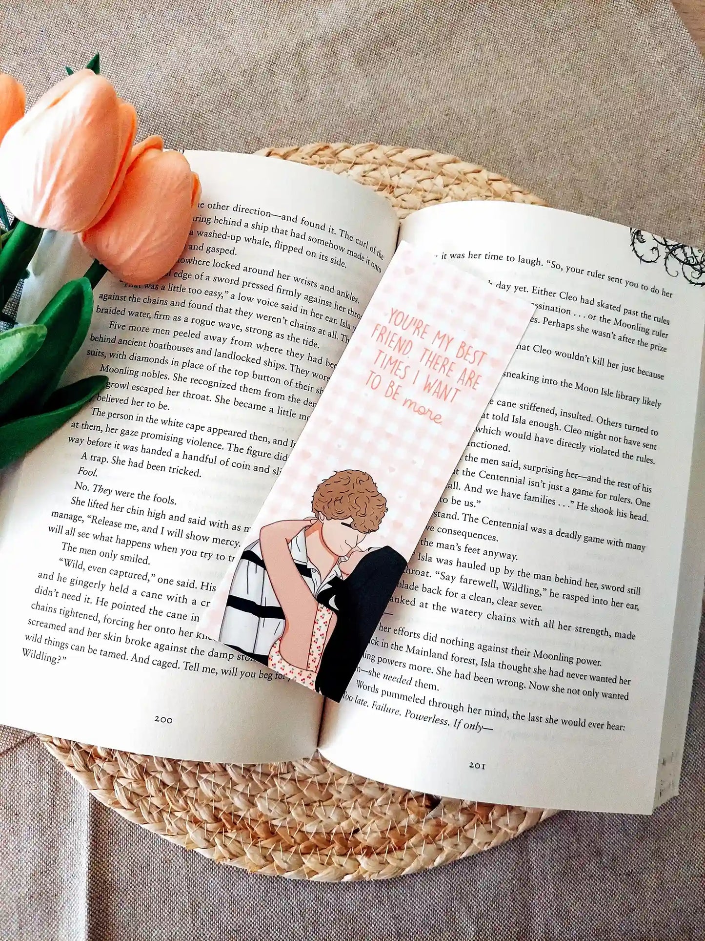Bookmark inspired by The Summer I Turned Pretty, featuring Belly and Jeremiah with the quote "You’re my best friend. There are times I want to be more." on a pink gingham background, resting on an open book.
