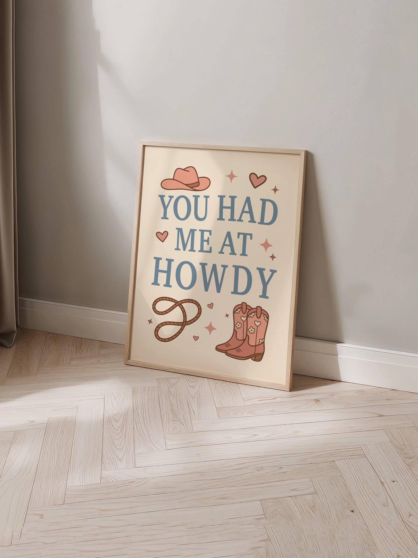 Art print inspired by cowboy romance books featuring the phrase "You Had Me at Howdy" with illustrated boots, a hat and rope displayed in a frame.